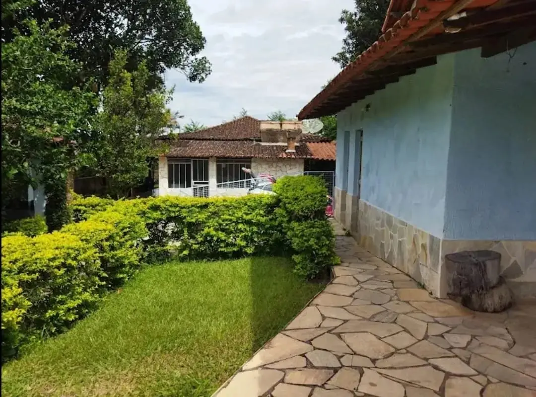 Fachada da casa da unidade, com jardim e caminho de pedra.